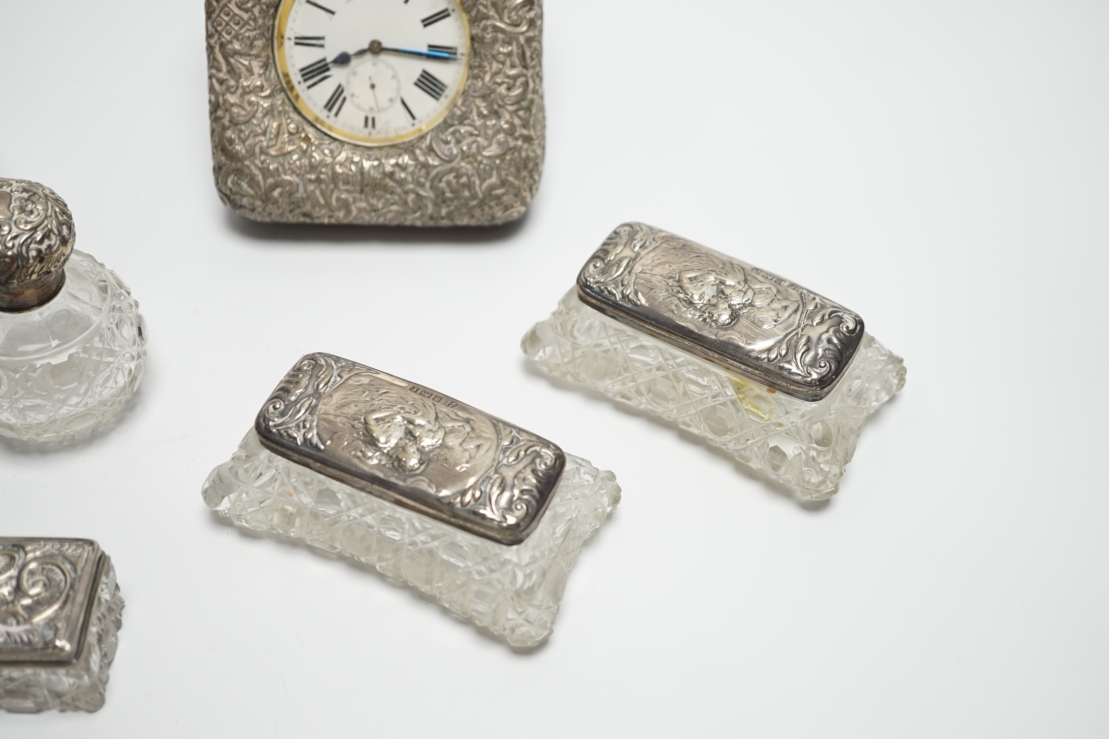 A late Victorian repousse silver mounted travelling pocket watch case, Birmingham, 1898, 11.6cm, with nickel cased pocket watch, together with five silver topped glass toilet jars.